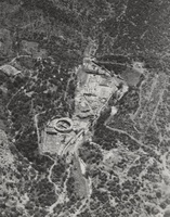 Aerial photo of archaeological site with remains of buildings surrounded by trees and hills