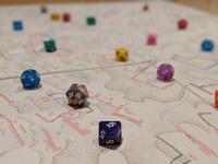 Photo of game dice of various colors on a topographical site plan.