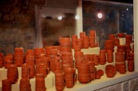 Photo of display case in museum containing stack of red ceramic pottery.
