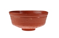 Footed terra cotta bowl with all-over decoration, including floral imagery, rosettes, and a bird