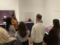 A group of people gathered around exhibition cases in ISAW gallery