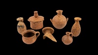 An array of different tan 7th century BCE Cretan and Corinthian clay vessels all different shapes and sizes with a black background