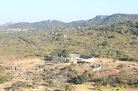 Photo of archaeological site on top of hill in a mountainous area, taken from a higher vantage point