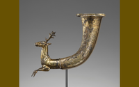 The forepart of a stag emerges from the curving body of this gilt silver rhyton. The eyes and the outstretched legs heighten the realistic effect of the stag