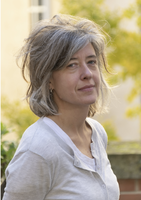 Headshot of Amy Bogaard standing outdoors with green foliage in the background.