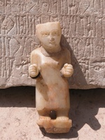Alabaster statue of a standing man wearing a robe in front a relief panel