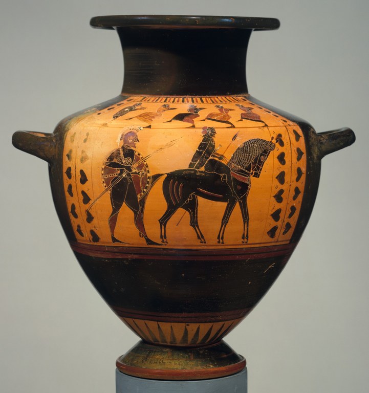 A tapered, shouldered ceramic vessel with two handles and narrow neck, glazed in black, orange, and red. A central panel depicts bearded soldiers. The shoulder depicts a row of four dancers, each with a raised leg, facing the flute player. Two of the dancers are clearly female; the other two appear to be male figures wearing women's clothing and animal ears.