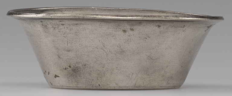 Photograph from the side of a silver bowl in the shape of a truncated cone with the narrow end for a base and a slightly flaring rim. No figurative decoration is visible.