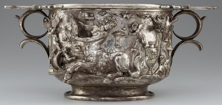 Photograph of a silver and gold two-handled cup, richly decorated with figures in raised relief.