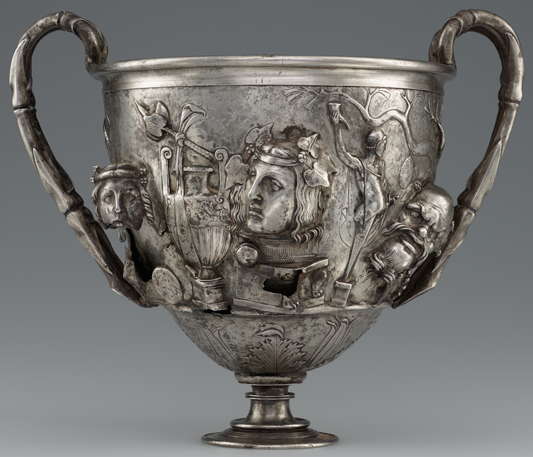 Photograph of a silver two-handled cup, richly decorated with figures in raised relief.