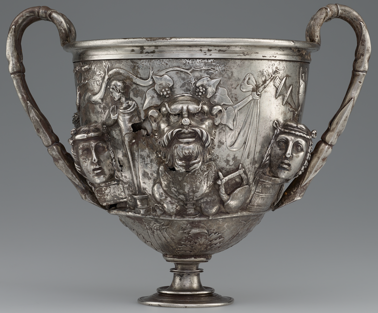 Photograph of a silver two-handled cup, richly decorated with figures in raised relief.