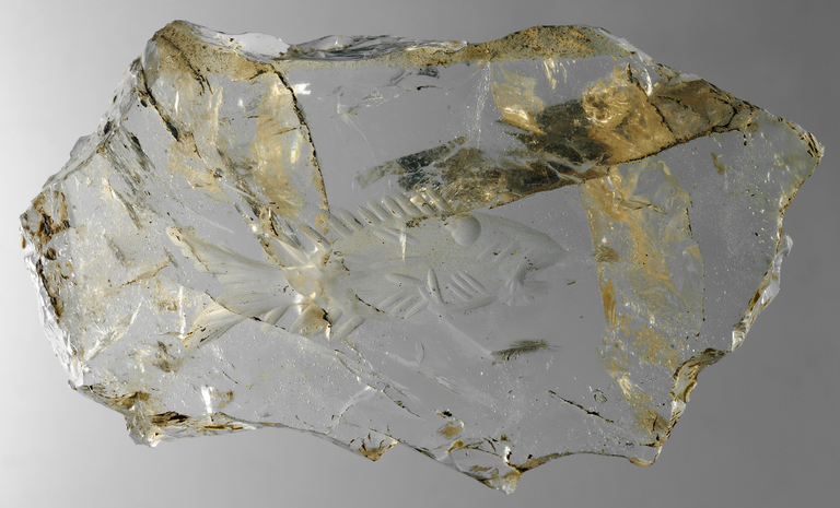 Photograph of a fragment of rock crystal into which a relief of a fish has been carved.