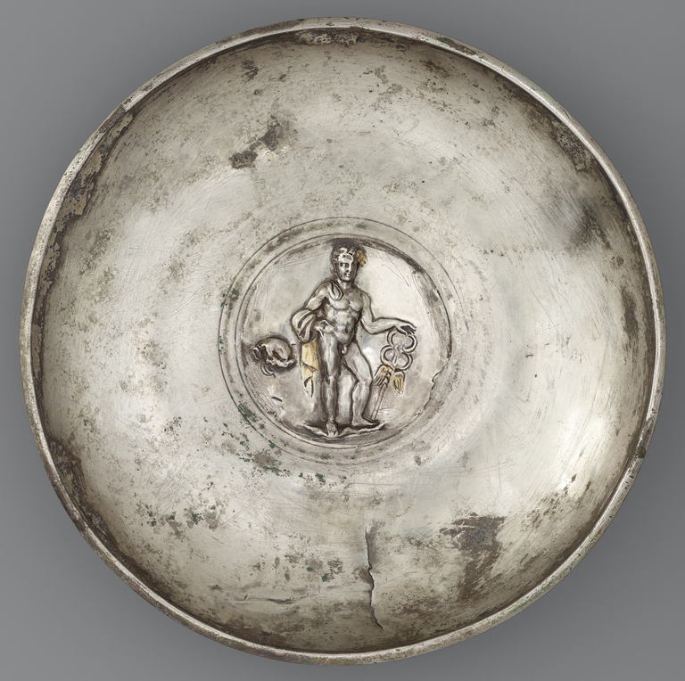 Photograph of a silver offering bowl with a large, central medallion in silver and gold depicting nude Mercury with caduceus.
