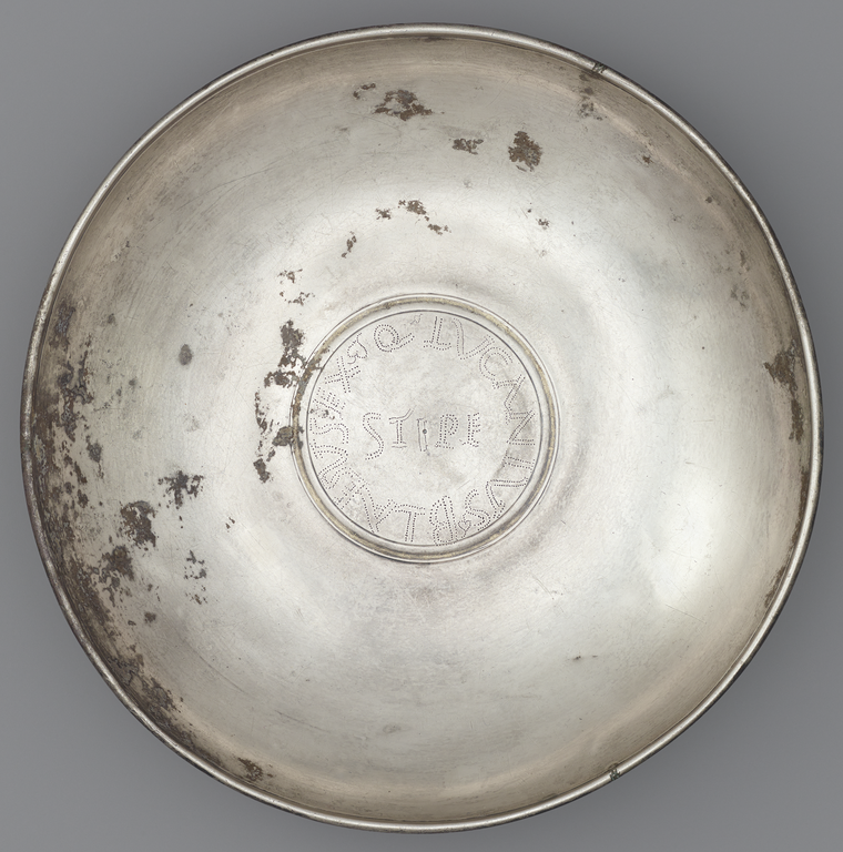 Photograph of a silver offering bowl with a large, central medallion on which has been incised a Latin inscription.