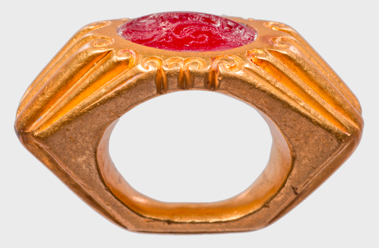 Photograph of a gold ring of hexagonal shape bearing a single carnelian intaglio.