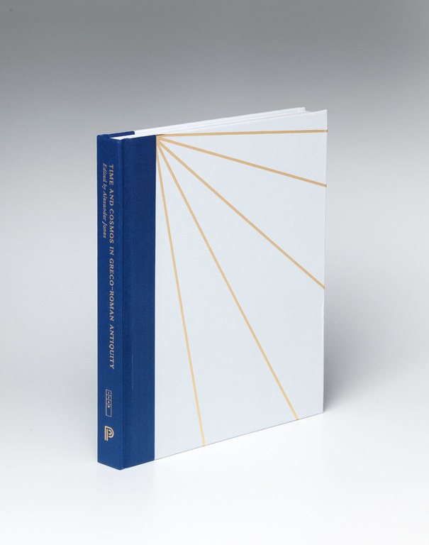 Photograph showing the hard-bound volume which features a set of four gold lines radiating from the top left of the white front cover. The binding of the spine is blue and features the title and editor's name in gold lettering.