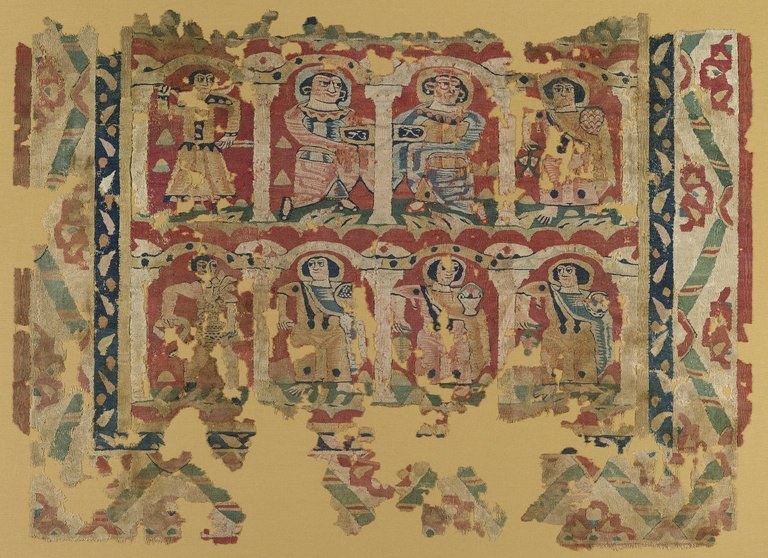 Tapestry weave of dyed wools and undyed linen, a: H. 103 cm; W. 148.2 cm. b: H. 5.5 cm; W. 15.5 cm. Egypt, ca. 6th–8th century CE. Brooklyn Museum, Charles Edwin Wilbour Fund, 46.128a–b. This wall hanging depicts an arcade of three stories or more of servants at work on behalf of the household. They carry flowers, baskets, and chalices piled high with fruit. In the fuller, original composition, these figures may have represented a calendar with personifications of the months, bearing the earth's bounty for each month, thereby ensuring prosperity for the household.
