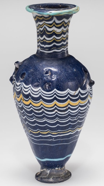 A blue vase or a cosmetic bottle with a trail decoration around the body. The bottle is navy blue and with white and bright yellow patterns on it.