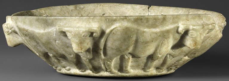 A shallow, conically-shaped marble bowl with two bulls shown in profile, facing right. The marble is an off-white color, with a small chip visible on the right side.