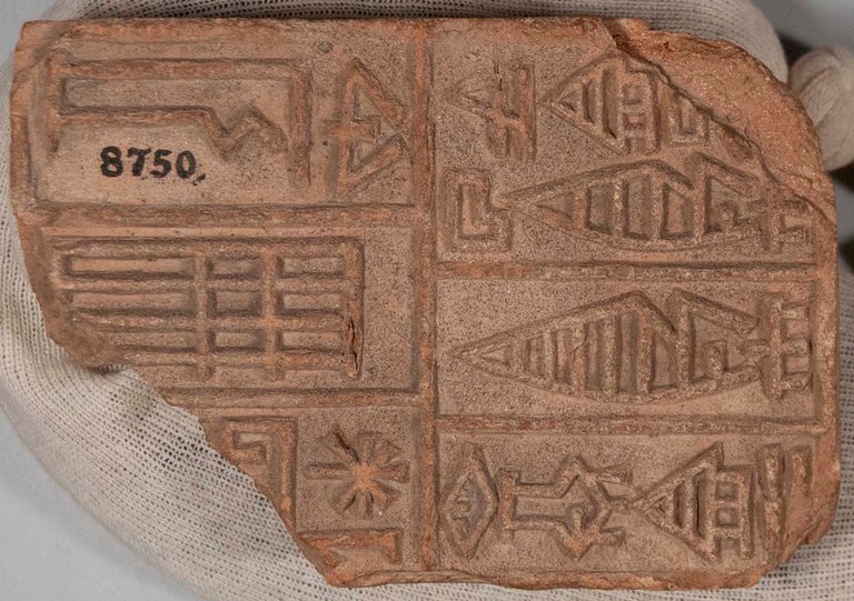 Molded and baked clay tablet with the corners chipped off. The tablet has cuneiform inscriptions on it.