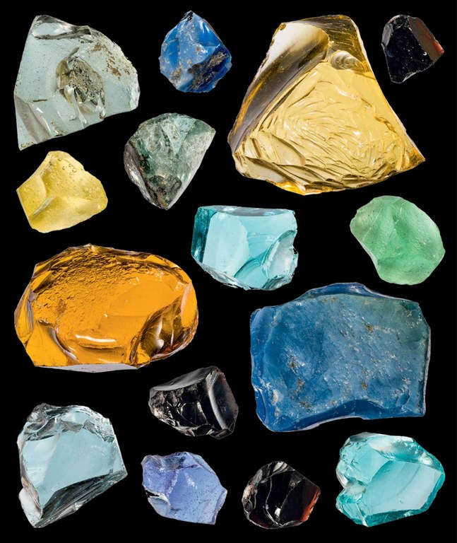image showing fifteen different rough pieces of cullet, in a variety of colors and sizes, on a black background