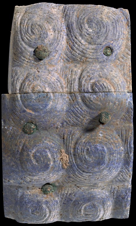 Fragmentary hair or beard inlay from a statue. The fragment is egyptian blue with spiral impressions.
