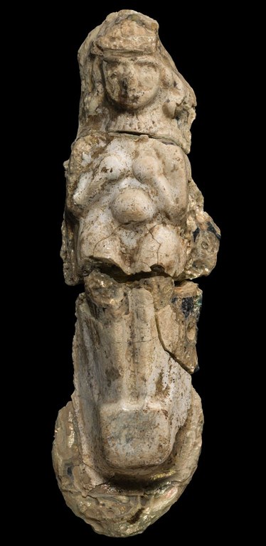 A molded ornament of a female figurine made of cast glass. The ornament is chipped and has many cracks.