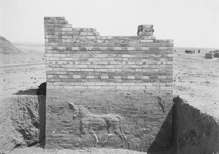 Black and white photograph of the portion of the Ishtar Gate with a molded bull on a brick wall.