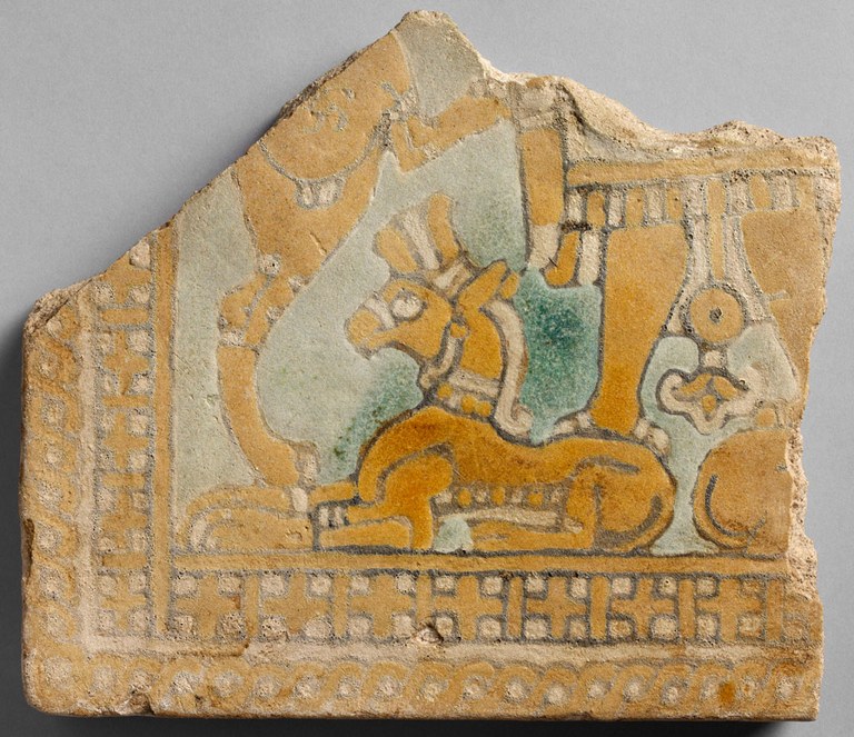 Fragmentary tile with a genie standing on a bull. The tile is orangish- yellow in color.