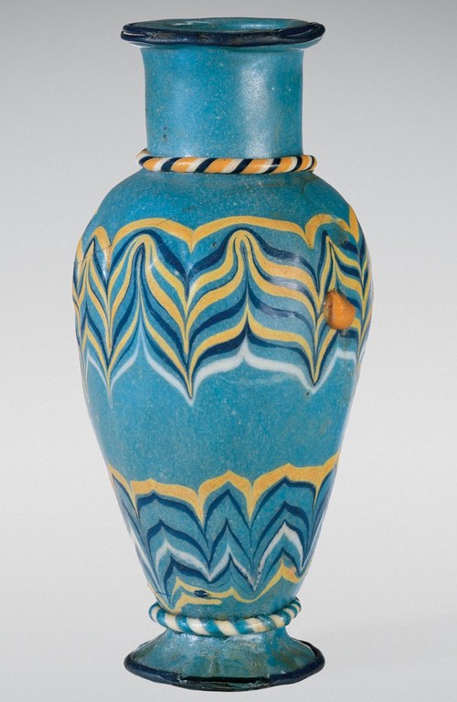 A blue vase with a trail decoration around the body. The vase is blue in color and yellow, orange, and navy blue patterns on it.
