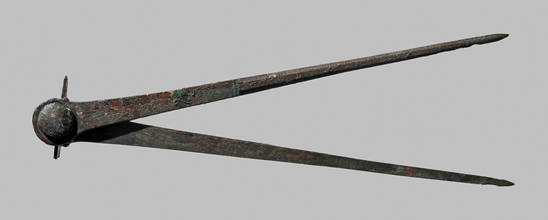 Two flat pieces of bronze in the shape of elongated right-angle triangles are joined on the short side of each with a knob that is pierced with a thin piece of metal.