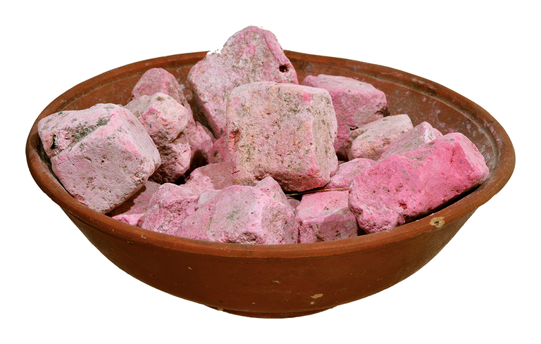 A terracotta plate with chunks of light-pink pigment.