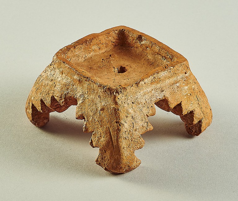 A table-like form with four legs. The interiors of the legs and the bottom of the horizontal surface are carved into multiple points.