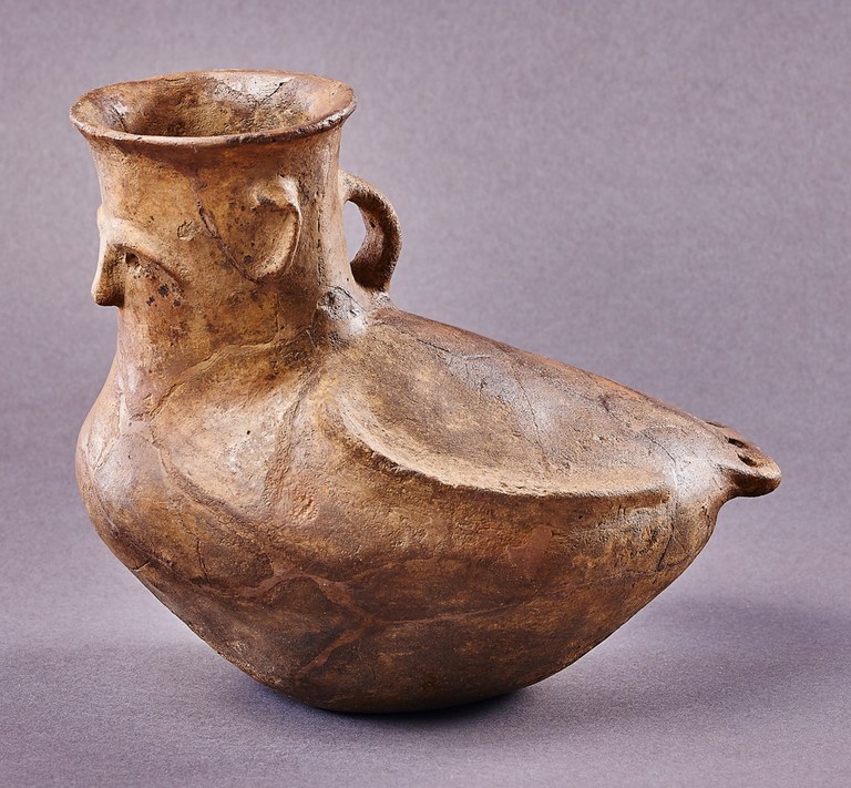 A globular vessel with one handle, the body of a bird, and a human face and ears on the neck.