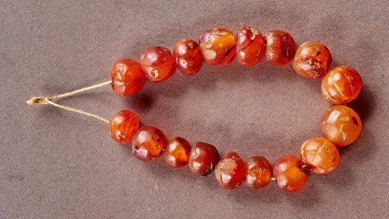 A string of seventeen red-orange beads.