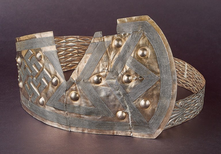 The fragments of this belt have been assembled to form a band decorated at the wide front with large raised dots and lines of small raised dots that form larger geometric patterns. It is decorated along the narrower back with diamond patterns.