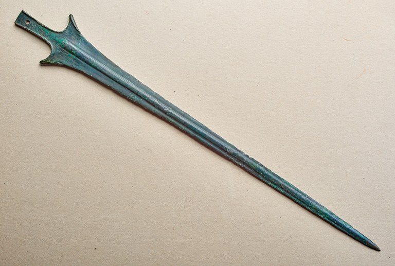 Below the handle, the blade has two prongs before tapering to a point. The fuller of the sword is rounded.