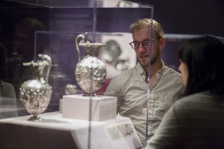 Two students look at silver vessels in display case