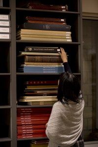 Student reaches for folio book in library stacks