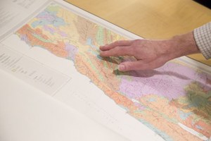 Hand pointing out location on map in folio volume