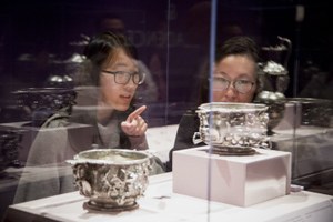 Two students discuss silver cups in display case