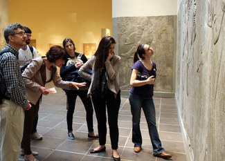 A group of people examine a large stone reliefe in a museum gallery.