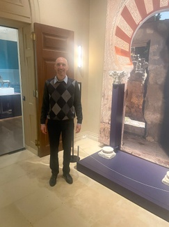 Peter Cobb standing in front of a museum exhibition featuring the columns of an Islamic arch from Spain.