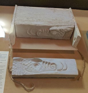 Replica of a brick mold and unfired clay brick from the construction of Babylon's Ishtar Gate, showing a part of the head of a mušhuššu dragon.