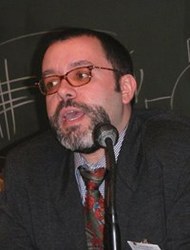  Man in jacket and tie sits in front of microphone