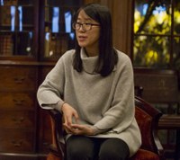 Woman sits in chair in wood-paneled room