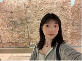 Yu Song pictured in front of a large wall of ancient reliefs