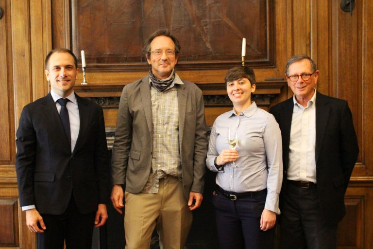 Four individuals pose in front of a fireplace in a formal library