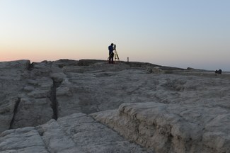 A silhouette of team members surveying the excavation at sunrise