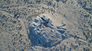 An aerial shot of the excavation site at Bashtepa, showing dirt rounds surrounding the dig site on an elevated mound